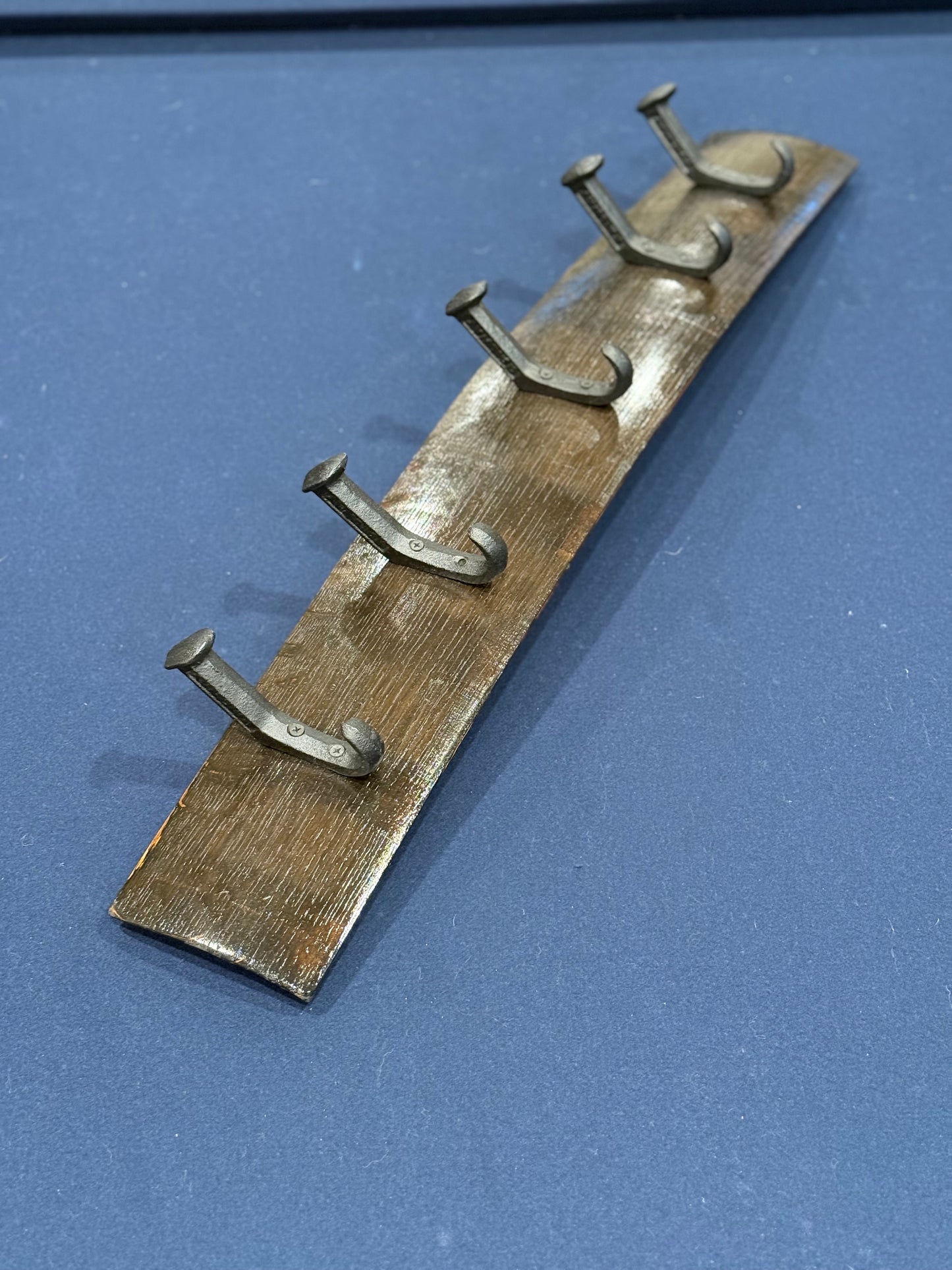 Oak bourbon barrel stave with five sturdy cast iron hooks in the shape of bent railroad spikes.
