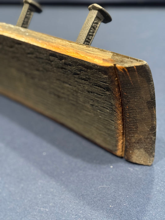 closer image of end of the oak bourbon barrel stave showing sturdy cast iron hooks in the shape of bent railroad spikes.